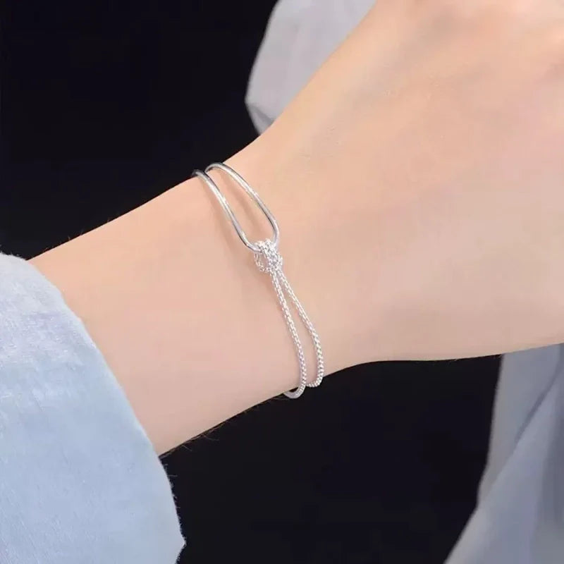 Bracelet asymétrique en argent 925 avec double chaîne maille serpent et jonc rigide entrelacés par un nœud.