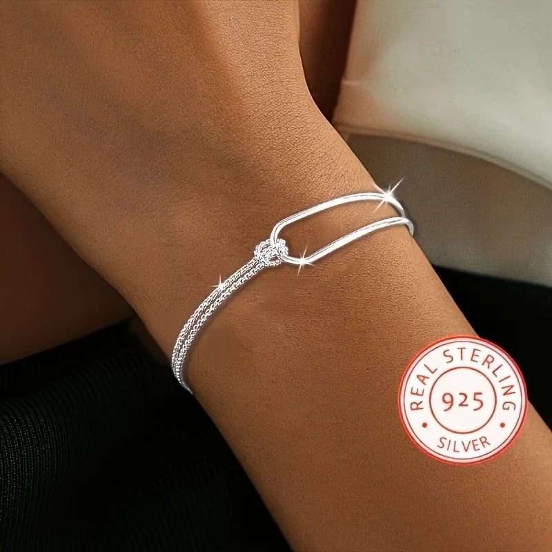 Bracelet asymétrique en argent 925 avec double chaîne maille serpent et jonc rigide entrelacés par un nœud.