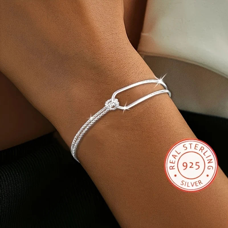 Bracelet asymétrique en argent 925 avec double chaîne maille serpent et jonc rigide entrelacés par un nœud.