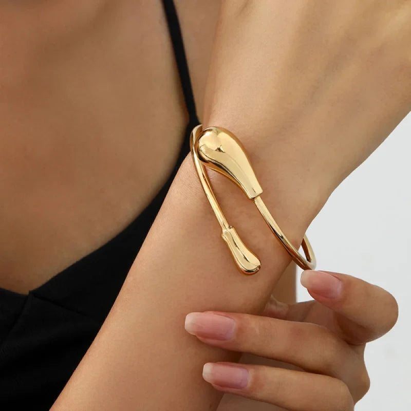 Bracelet doré au design organique et bombé, style goutte d'eau minimaliste portée au poignet
