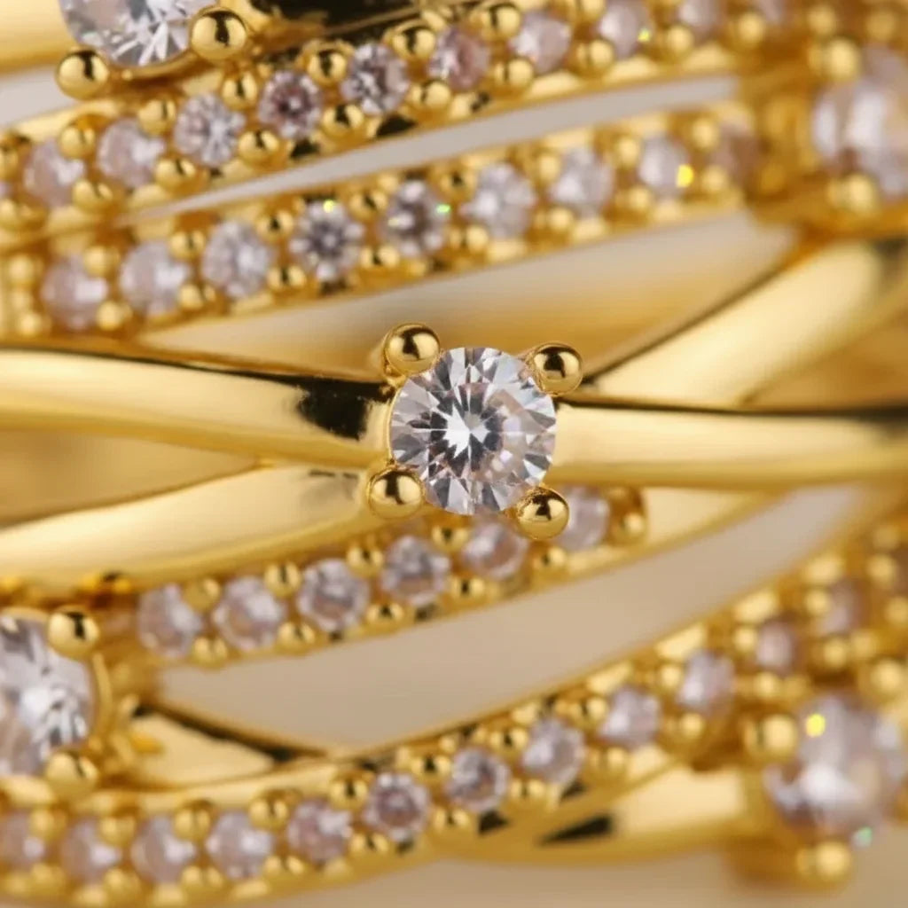 Grosse bague dorée multi-rangs entrelacée sertie de strass portés à l'annulaire d'une femme - Style chic et festif