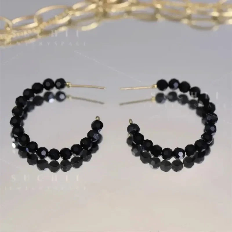 Boucles d'oreilles créoles ouvertes composées de perles à facettes noires, monture dorée - Style chic et élégant.