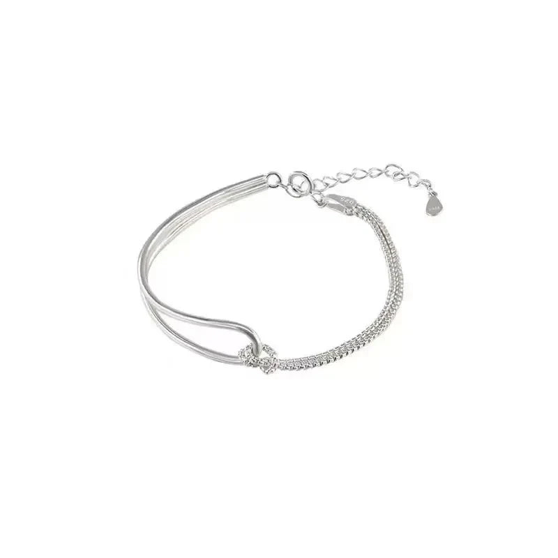 Bracelet asymétrique en argent 925 avec double chaîne maille serpent et jonc rigide entrelacés par un nœud.